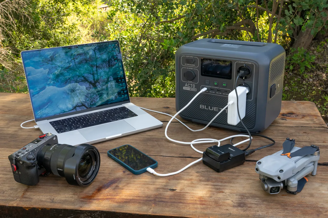 BLUETTI AC70 carregando notebook, celular, câmera e drone simultaneamente ao ar livre